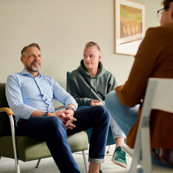 Behandelkamer jongere man gesprek lachen behandelaar